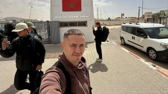 Tom Ruck prend un selfie devant le poste frontière de Guerguerat