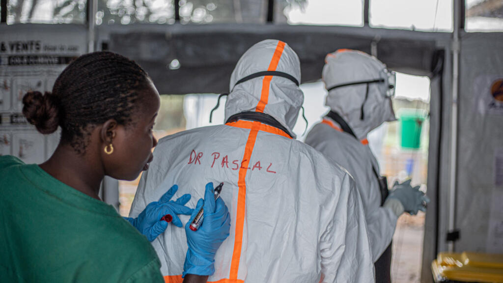 Agent d'hygiène préparant l'équipement de protection d'un médecin avant son entrée dans un centre de traitement Ebola à Bunia, en Ituri
